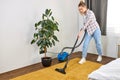 Woman in casual wear vacuum cleaning yellow carpet, tidying white modern living room. Home, housekeeping concept Royalty Free Stock Photo