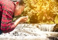 Woman catches running pure water in her cupped hands at waterfall. Conservation of natural resources