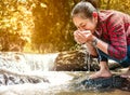 Woman catches running pure water in her cupped hands at waterfall. Conservation of natural resources