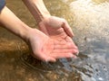 Woman catches running water in her cupped hands at waterfall.