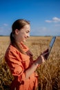 Woman caucasian technologist agronomist with tablet computer in the field of wheat checking quality and growth of crops for