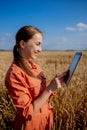 Woman caucasian technologist agronomist with tablet computer in the field of wheat checking quality and growth of crops for