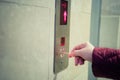 A woman pushing an elevator button with a toothpick instead of using her hand.