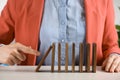 Woman causing chain reaction by pushing domino tile at table, closeup Royalty Free Stock Photo