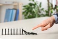 Woman causing chain reaction by pushing domino tile at table, closeup Royalty Free Stock Photo