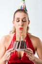 Woman celebrating birthday with cake blowing candles out Royalty Free Stock Photo