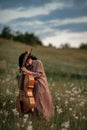 Woman cellist prepares to play at flowering meadow.