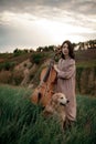 Woman cellist prepares to play at meadow next to dog. Royalty Free Stock Photo