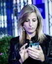 Woman with cellphone in hand writing a message, long-haired blonde.