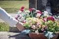 Woman at cemetery put flowers on the grave in sunny day