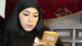 Woman with chador headscarf using mobile phone