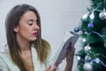 Woman in chair in front of Christmas tree reading book. Woman reading book near Christmas tree. Royalty Free Stock Photo