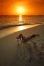 Woman in chaise-lounge relaxing on beach