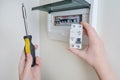 A woman changes an automatic fuse in a home electrical panel. Self repair and replacement of electricity equipment in the