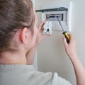 A woman changes an automatic fuse in a home electrical panel. Self repair and replacement of electricity equipment in the