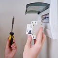 A woman changes an automatic fuse in a home electrical panel. Self repair and replacement of electricity equipment in the