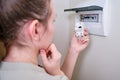 A woman changes an automatic fuse in a home electrical panel. Self repair and replacement of electricity equipment in the