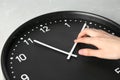 Woman changing time on big black clock
