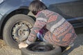 Woman changing a wheel on a car on the empty road Royalty Free Stock Photo