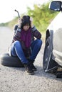 Woman changing a wheel on a car on the empty road Royalty Free Stock Photo