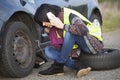 Woman changing a wheel on a car on the empty road Royalty Free Stock Photo