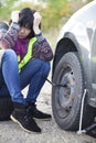 Woman changing a wheel on a car on the empty road Royalty Free Stock Photo