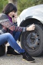 Woman changing a wheel on a car on the empty road Royalty Free Stock Photo