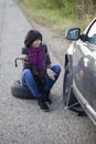 Woman changing a wheel on a car on the empty road Royalty Free Stock Photo