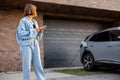 Woman charges her electric car near a house Royalty Free Stock Photo
