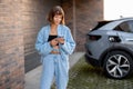 Woman charges her electric car near a house Royalty Free Stock Photo