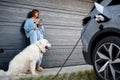 Woman charges her electric car near a house Royalty Free Stock Photo