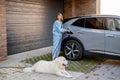 Woman charges her electric car near a house Royalty Free Stock Photo