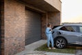 Woman charges her electric car near a house Royalty Free Stock Photo