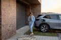 Woman charges her electric car near a house Royalty Free Stock Photo