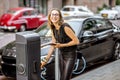 Woman charging electric car outdoors Royalty Free Stock Photo