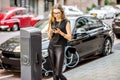 Woman charging electric car outdoors Royalty Free Stock Photo