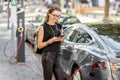 Woman charging electric car outdoors Royalty Free Stock Photo