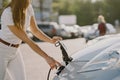 Woman charging electro car at the electric gas station