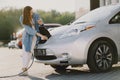 Woman charging electro car at the electric gas station