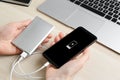 Woman charging mobile phone with power bank at table, closeup Royalty Free Stock Photo