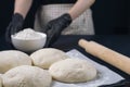 Woman in checkered apron and black gloves holds a flour bowl behind baking tray with pieces of yeast dough. Process of making Royalty Free Stock Photo