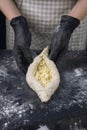 Woman in checkered apron and black gloves holds raw khachapuri. Process of making bakery. Adjarian Khachapuri Recipe Ã¢â¬â Georgian Royalty Free Stock Photo