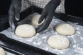 Woman in checkered apron and black gloves put a piece of yeast dough in baking tray. Process of making bakery. Adjarian Khachapuri Royalty Free Stock Photo