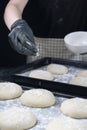 Woman in checkered apron and black gloves are sprinkling with flour a piece of yeast dough in baking tray. Process of making Royalty Free Stock Photo