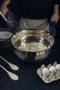 Woman in checkered apron mixing wheat flour, milk and yeast with wooden spoon. Process of making bakery. Adjarian Khachapuri