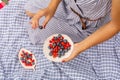 Woman in checkered stylish dress take berry from berries plate. Outdoor picnic
