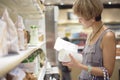 Woman checking info on package in supermarket