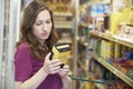 Woman Checking Labelling On Box In Supermarket