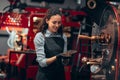 Woman checking the quality of the coffee beans standing near the roaster machine at the roastery. Mixing roasted coffee Royalty Free Stock Photo