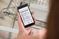 Woman Checking Shopping List On Smartphone In Supermarket Royalty Free Stock Photo